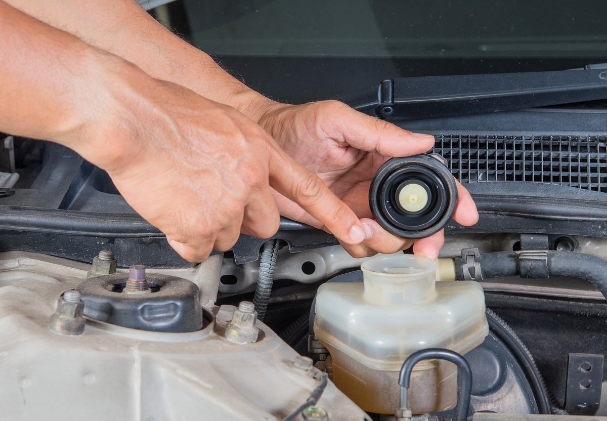 Technician checking the brake fluid reservoir under the hood of a vehicle