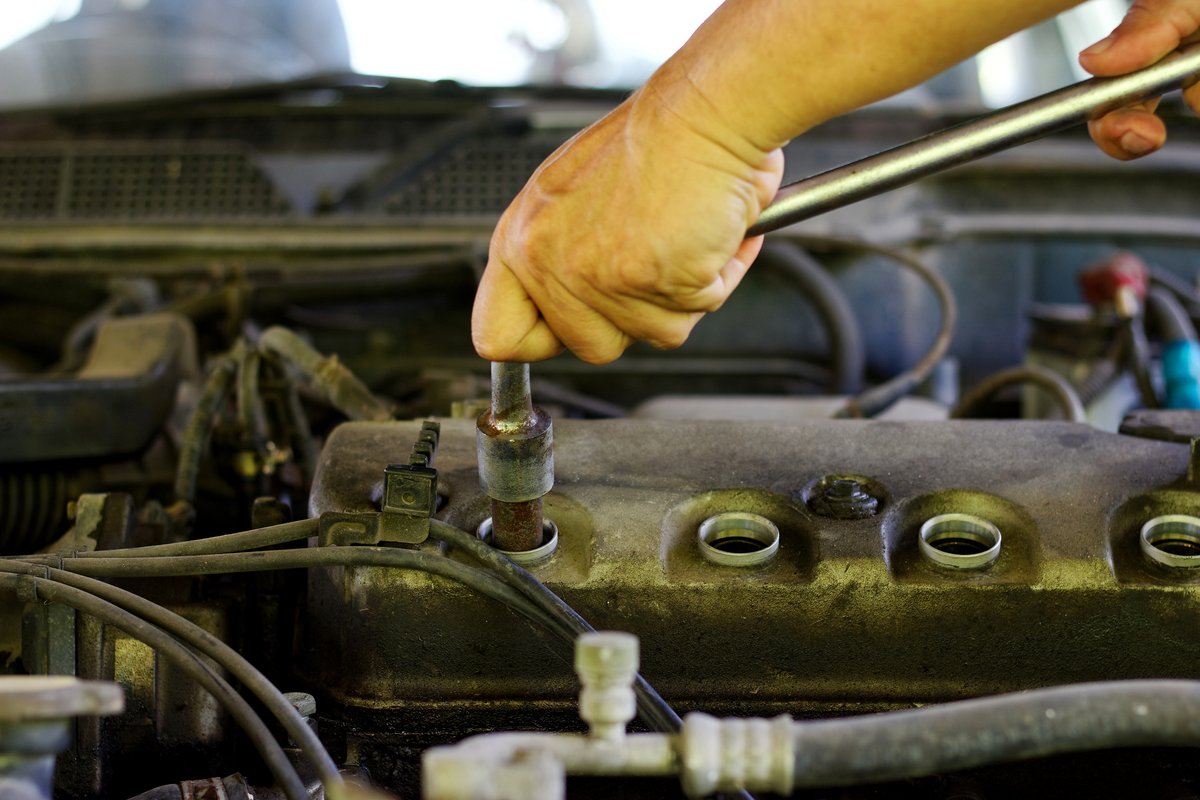 Technician working with a wrench on engine mounting hardware in an engine bay