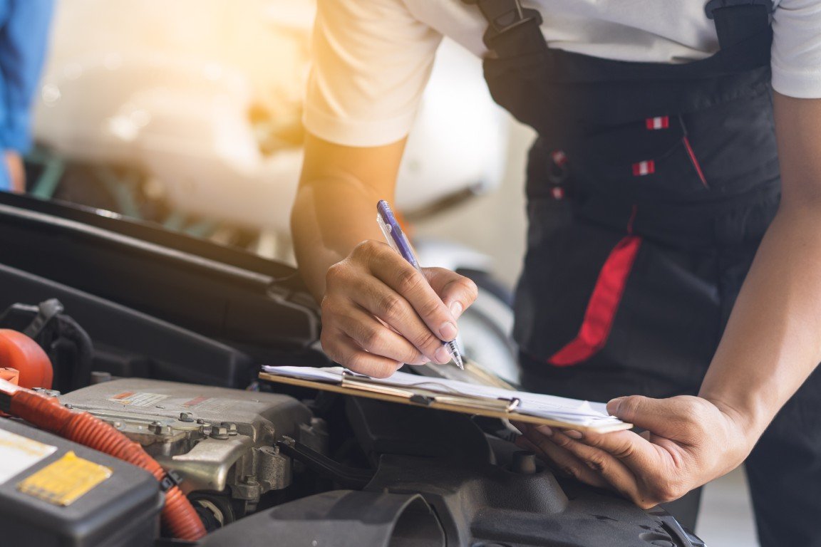 Service advisor reviewing a written repair estimate with a customer at a vehicle